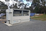 Large sea container sized vanadium flow, or redox, battery, cover open, next to solar panels in bush setting