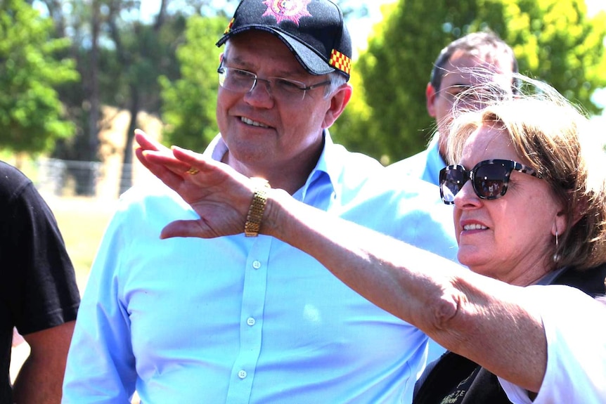 Prime Minister Scott Morrison wears a firefighter's cap.