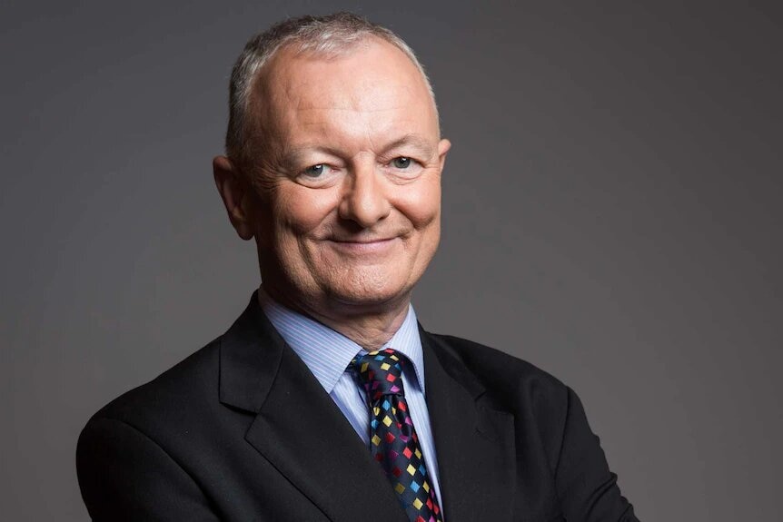 ABC election expert Antony Green smiles at the camera with his hands clasped behind his back.