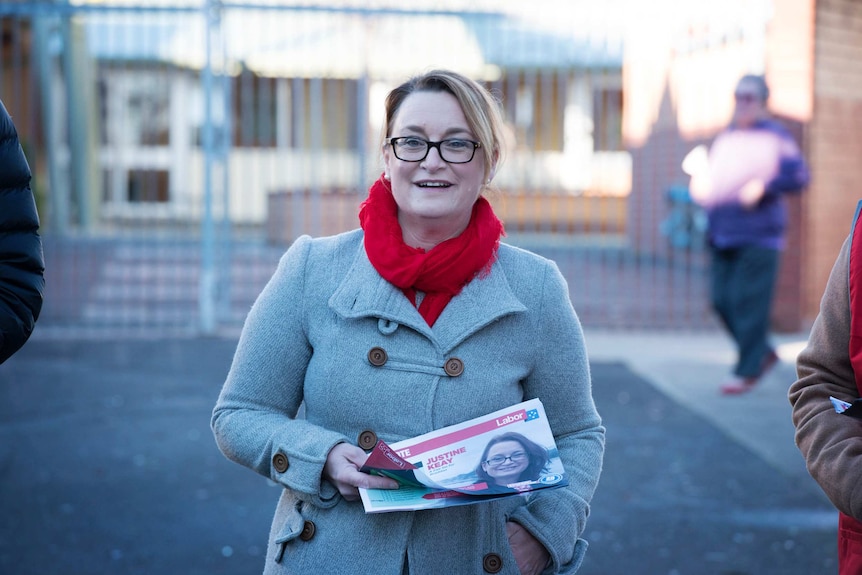 Justine Keay smiles while holding fliers.