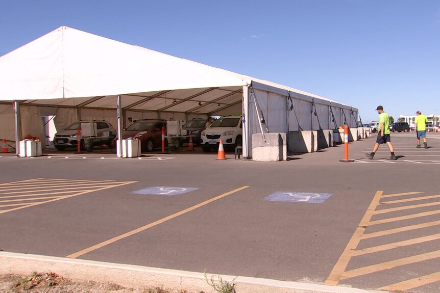 Cars waiting under a marquee with buildings behind