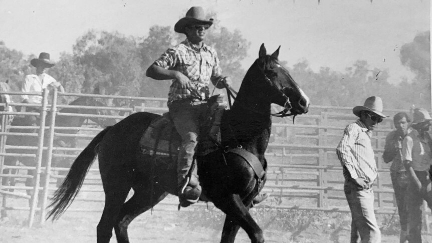 Black and white photo of man with sunglasses riding horse