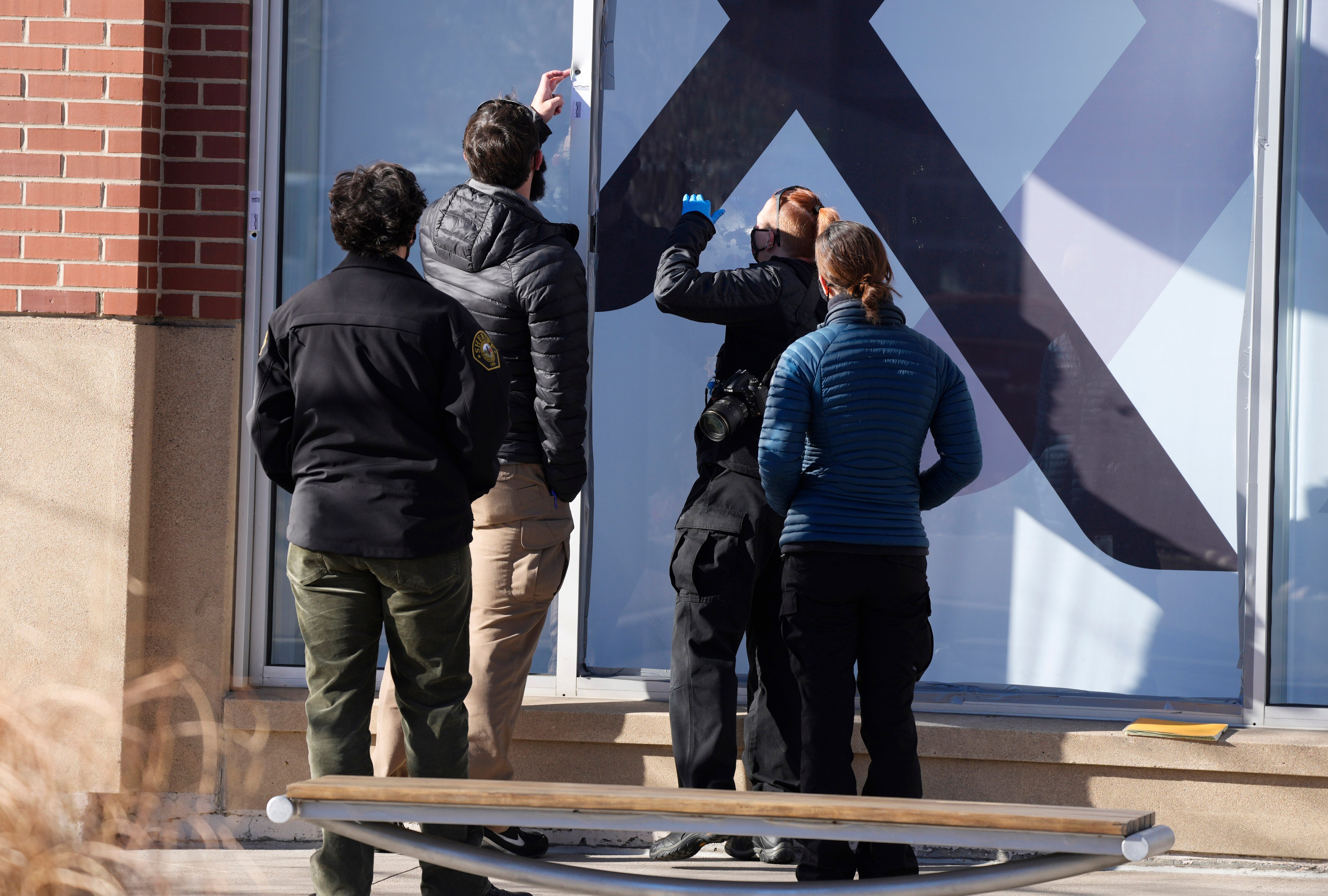 Investigators recover evidence from a window frame outside an Xfinity store in Denver.