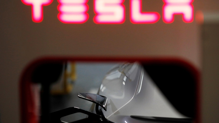 A red neon sign reads Tesla