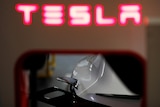 A red neon sign reads Tesla
