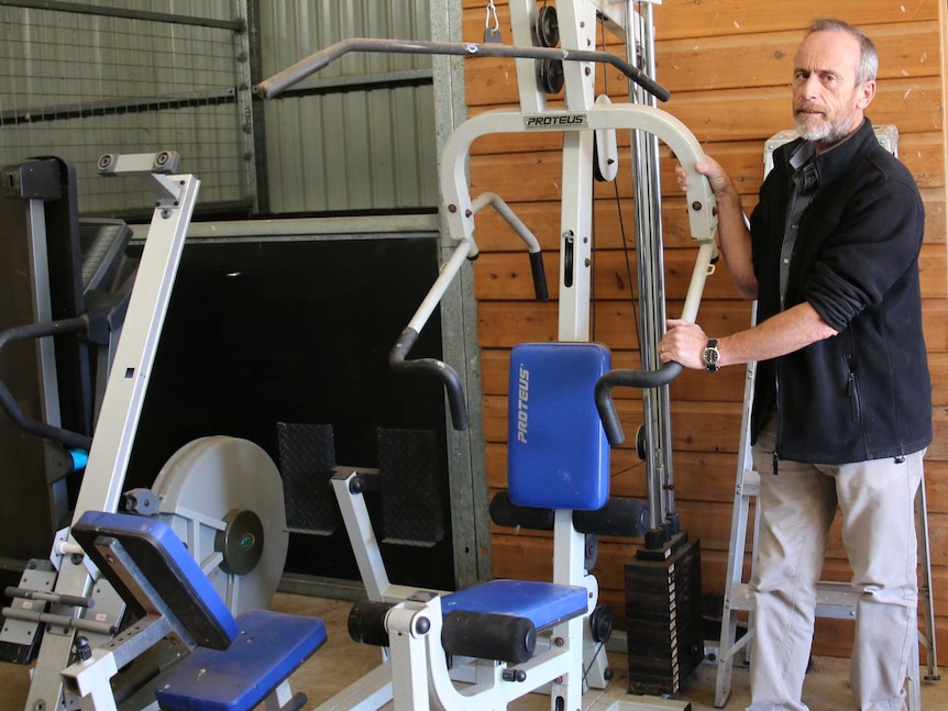 Ian stands with his gym equipment in his barn.