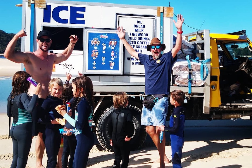 Actor Chris Hemsworth and six children in front of ice truck on beach with Rob Gough