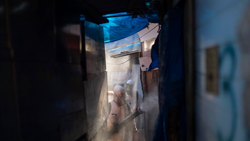 Volunteers wearing protective suits disinfect an alleyway in Brazil.