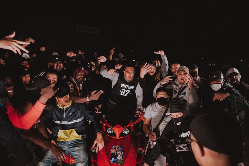 A group of rappers standing in a street at night