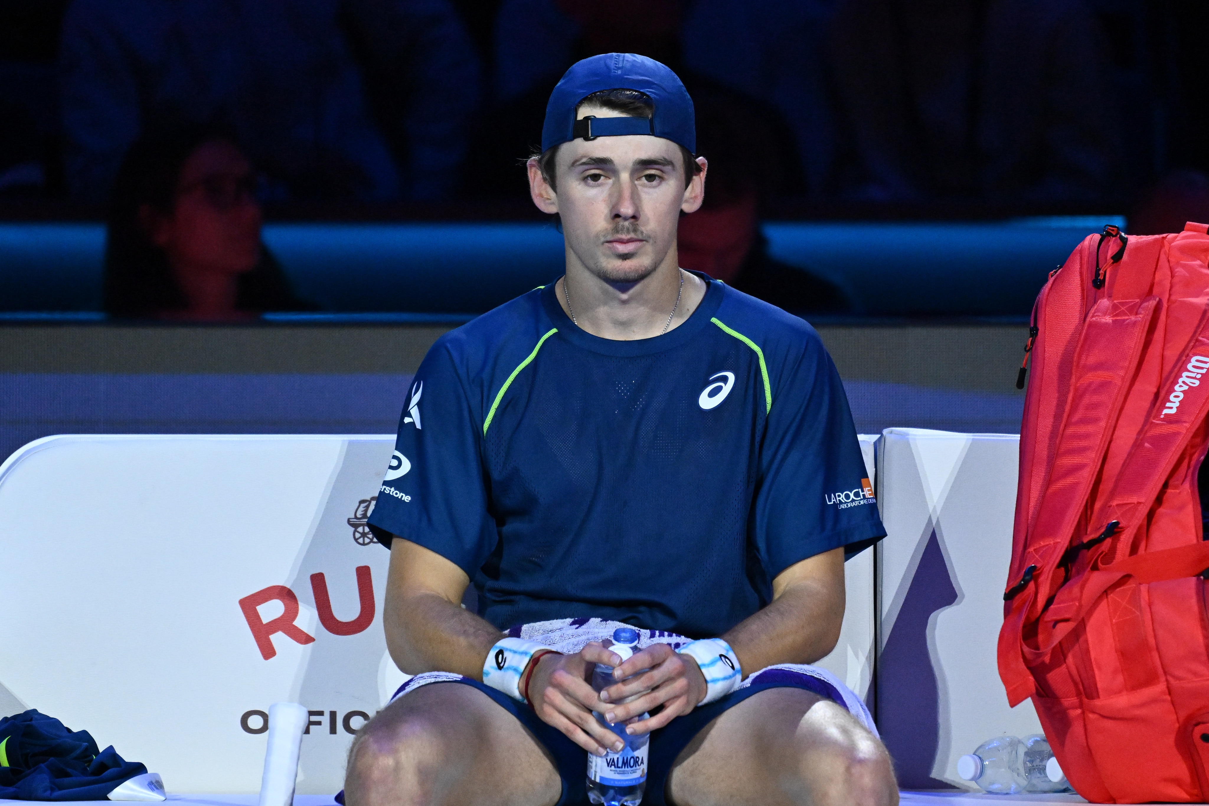 Alex de Minaur sits on the bench and looks disappointed
