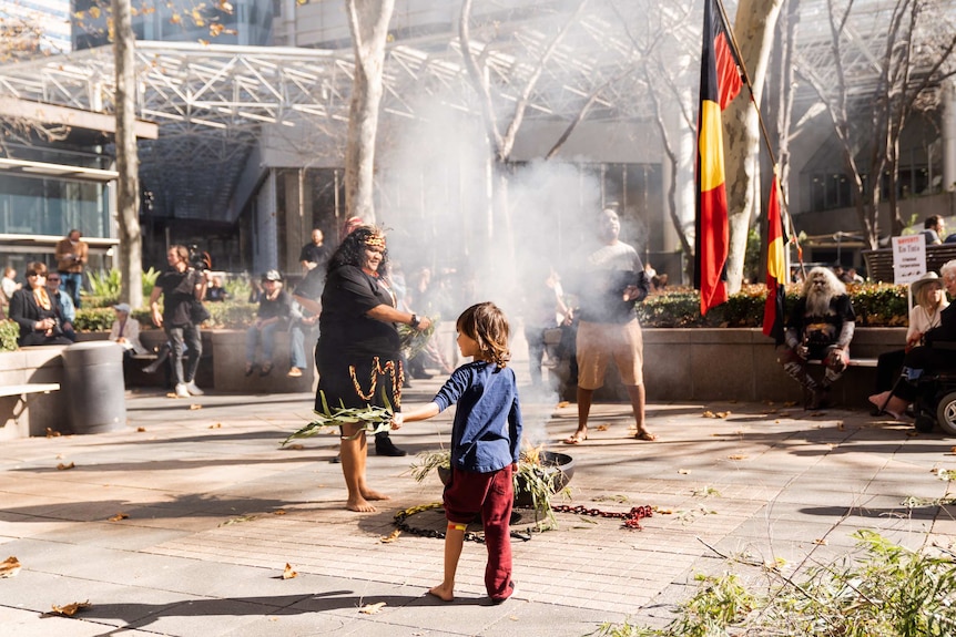 A child stands in front of a smoking ceremony fire outside Rio Tinto offices in Perth CBD.