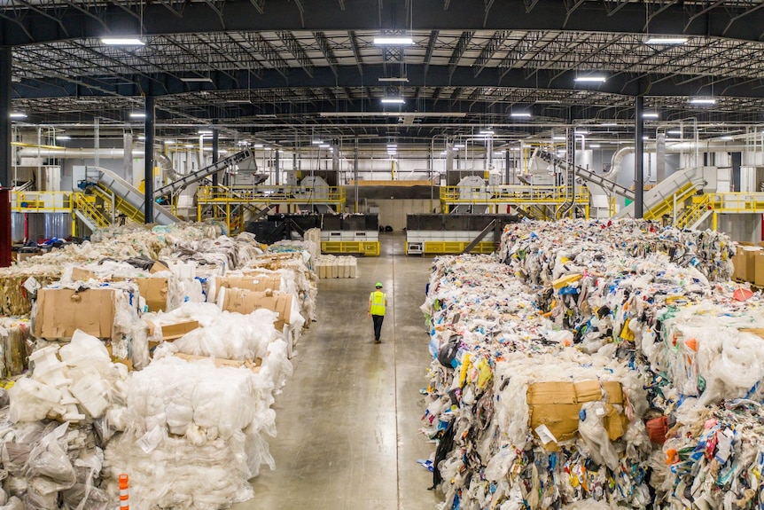 Wide shot of plastic waste being recycled inside a shed 