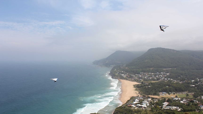 The view south looking towards Wollongong from Bald Hill with hang gliders in the air.