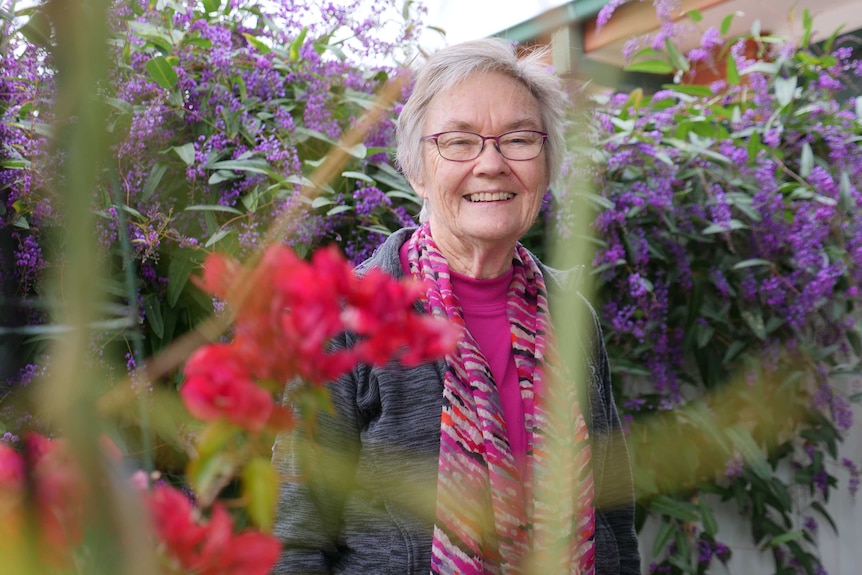 Marie Murphy smiles with purple flowers in the background.