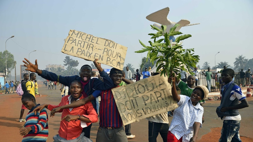 Anti-Seleka demonstrators pose with placards reading "Michel must leave", "Djotodia must leave, we want peace".