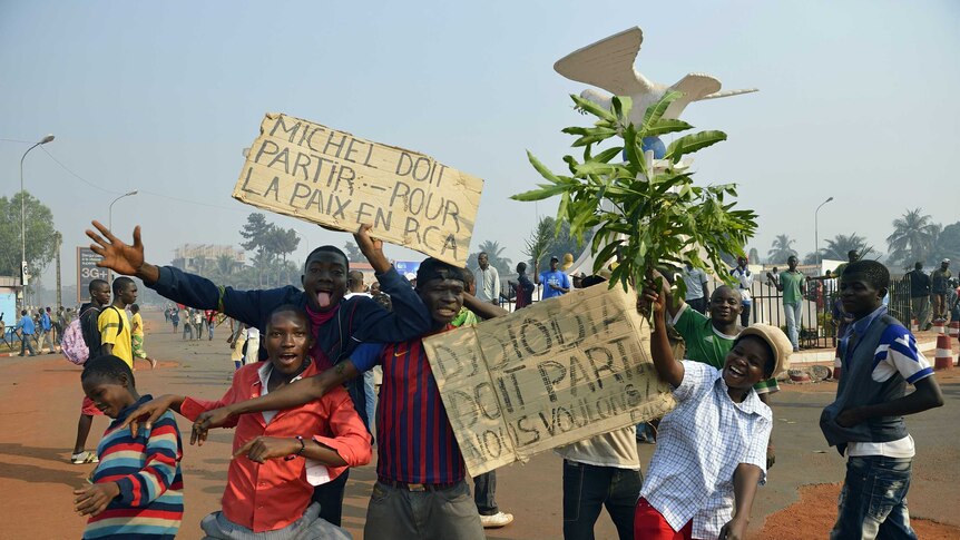 Demonstrators pose with placards reading "Michel must leave" and "Djotodia must leave, we want peace".