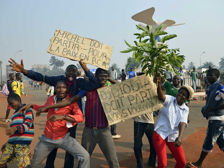 Demonstrators pose with placards reading "Michel must leave" and "Djotodia must leave, we want peace".