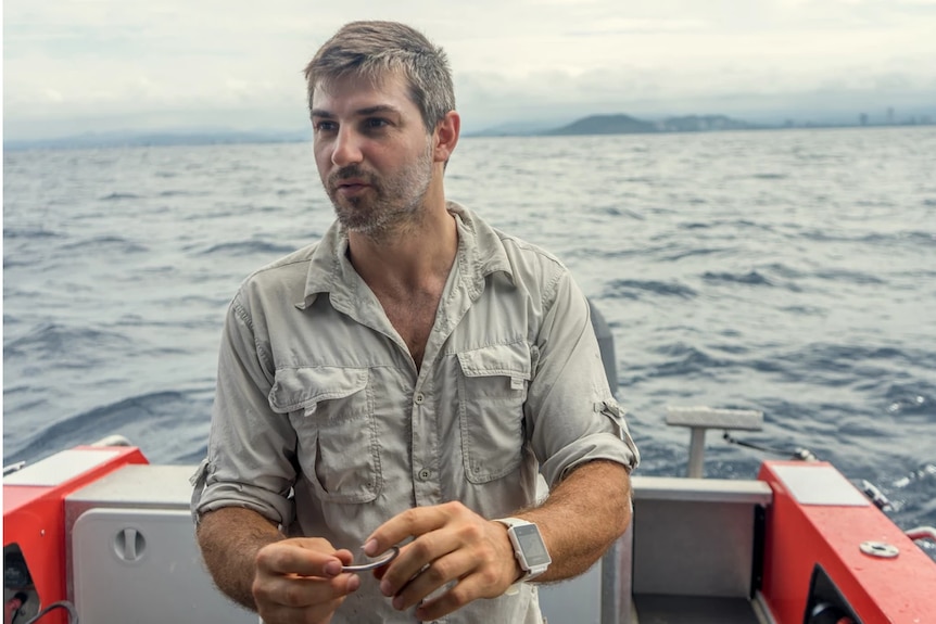 Dr Johan Gustafson standing on a research boat off the Gold Coast