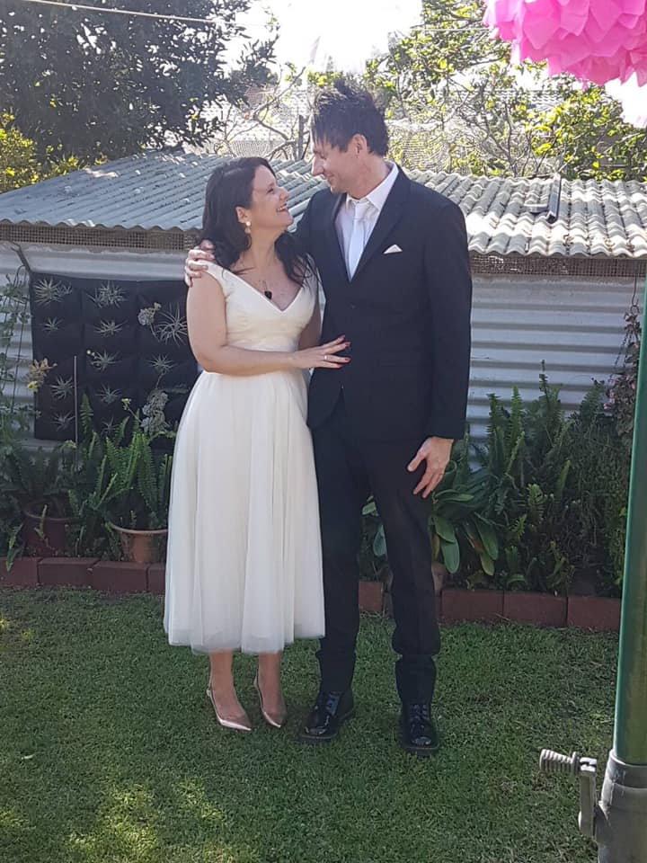 Jo and Luke in formal wear in a backyard.