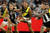 Shai Bolon kicks the ball as a number of Collingwood players attempt to tackle him