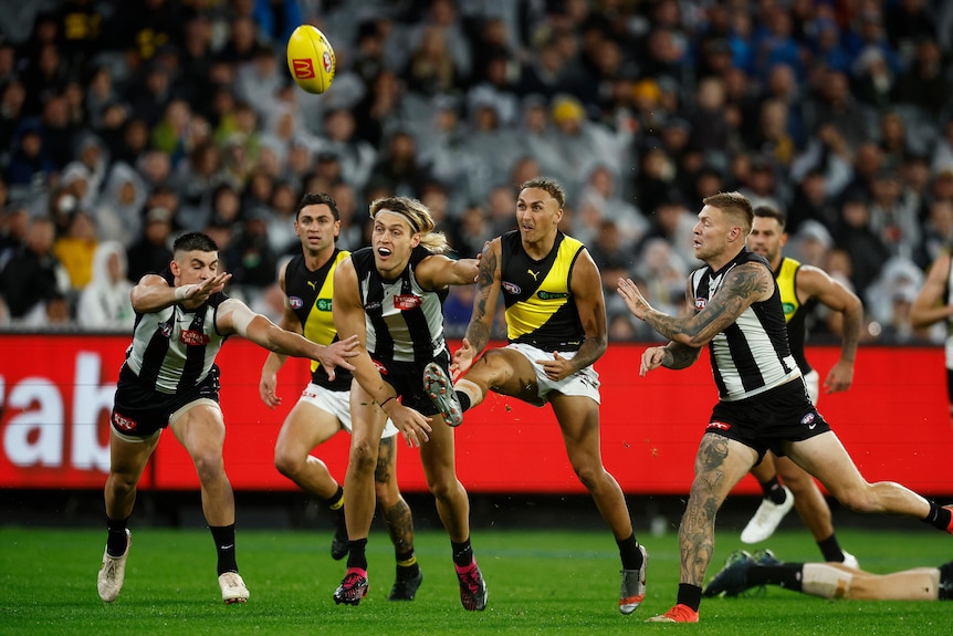Shai Bolon kicks the ball as a number of Collingwood players attempt to tackle him