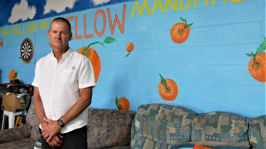 A man standing in front of couches in an empty backpacker hostel