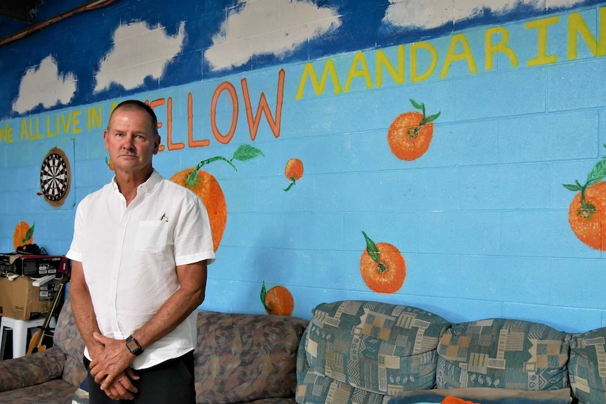 A man standing in front of couches in an empty backpacker hostel