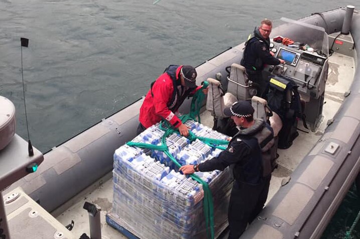 A pallet of water is loaded onto a fisheries patrol boat.