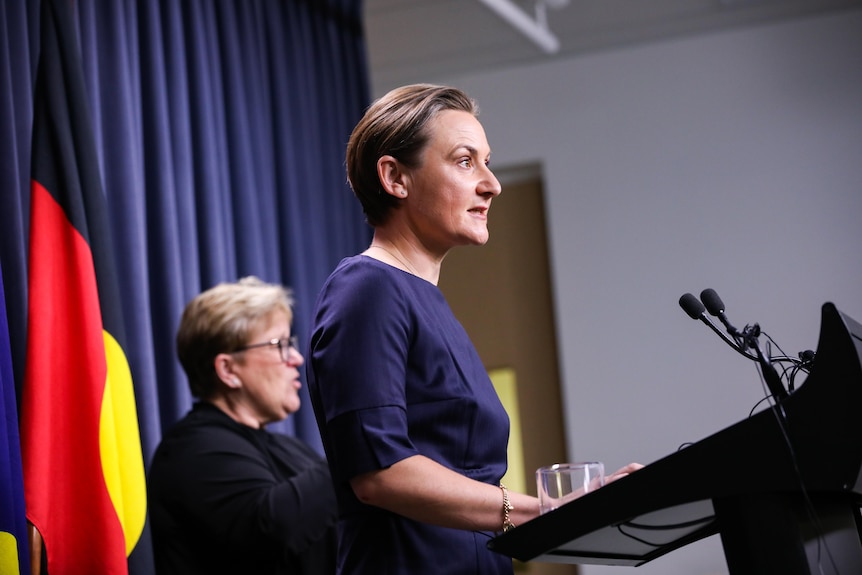 A woman with short hair standing at a lectern.