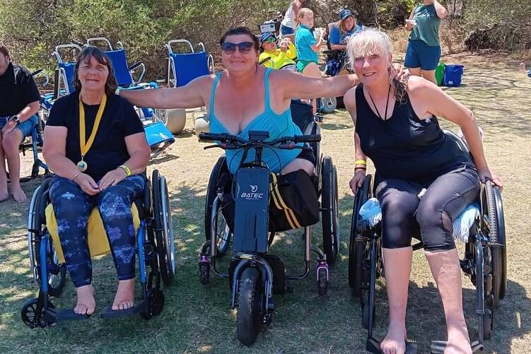 Three women sitting in wheelchairs side-by-side.