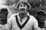 Rod Marsh smiles while holding up his hands while wearing wicketkeeping gloves