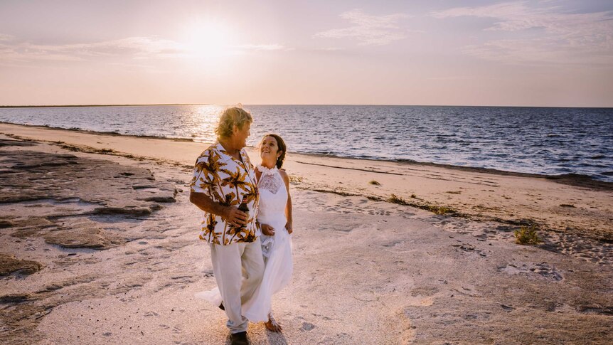 Lyn and Doug Scouller smile at one another on their wedding day on the Karumba coastline during a sunset.
