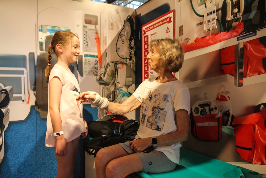 A little girl pretends to be a nurse with a woman with a bandaged hand