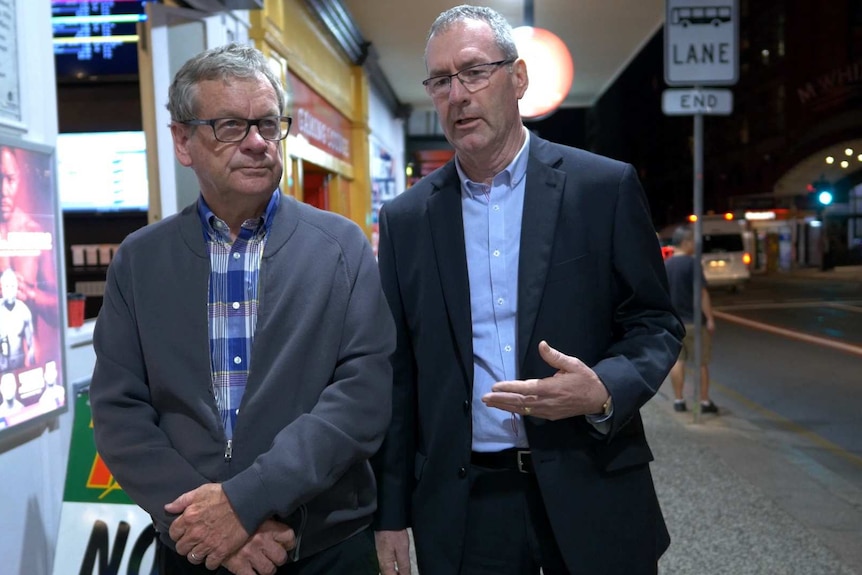 Journalist Chris Masters and AFP officer Dave Moore walk down the street.