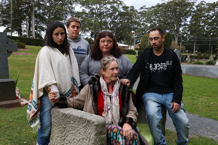 A group of people at a gravesite looking sad.