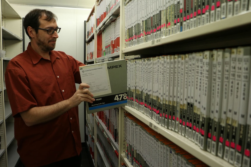 Jon Steiner pulling out a quarter inch audio tape from a shelf in the sound library.