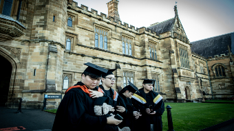 Four students graduating from university with a building in the background