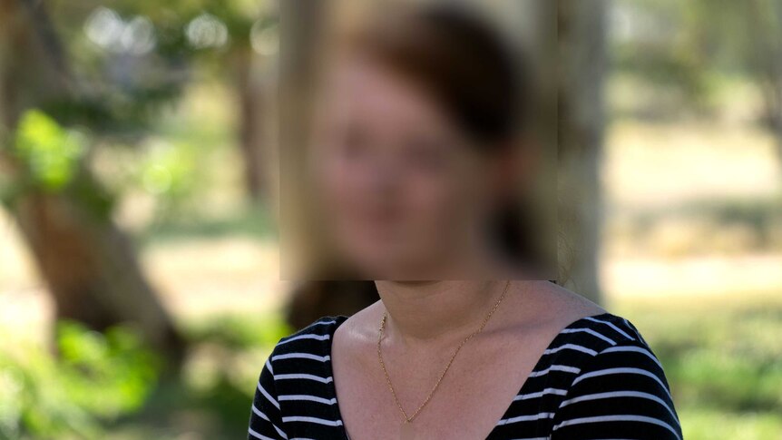 A blurred photograph of a woman in a park.