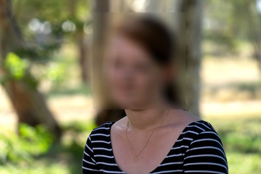 A blurred photograph of a woman in a park.