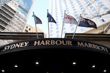 a low angle shot of a sign showing sydney harbour marriott underneath flags