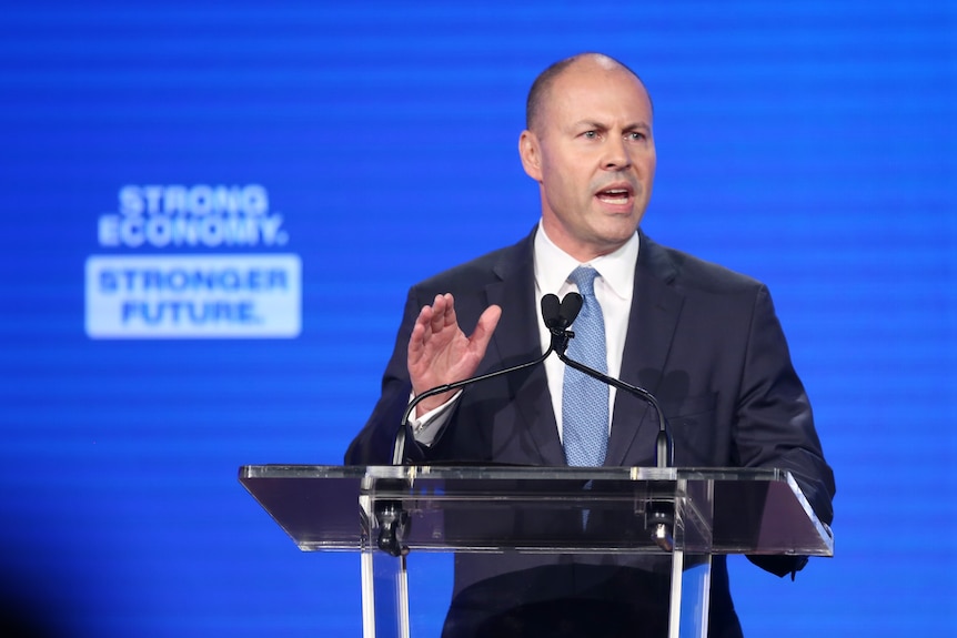 Josh Frydenberg fait des gestes tout en parlant devant un pupitre.