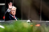 Trump waves as he exits a car.