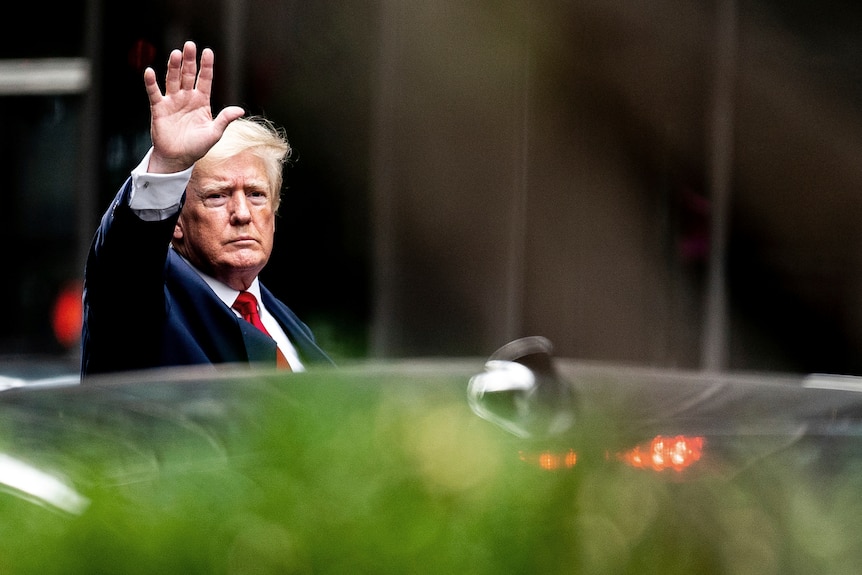 Trump saluta mentre scende dall'auto.