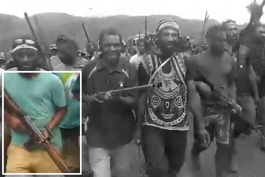 A man in a teal shirt carries a rifle and a graphic box highlights him among the group of men