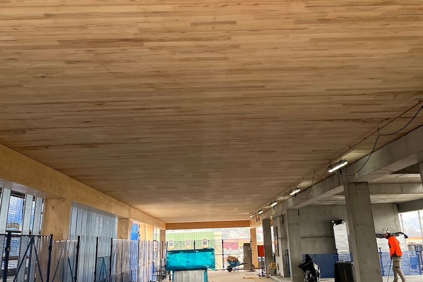 A long timber ceiling stands above office space still under construction 