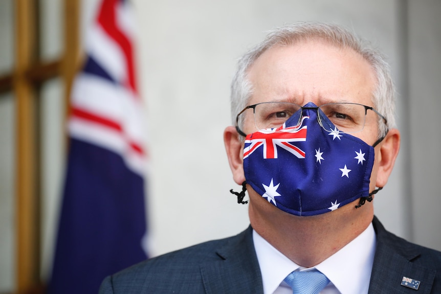 Tight shot of Morrison is staring straight ahead wearing a mask with the Australian flag on it.