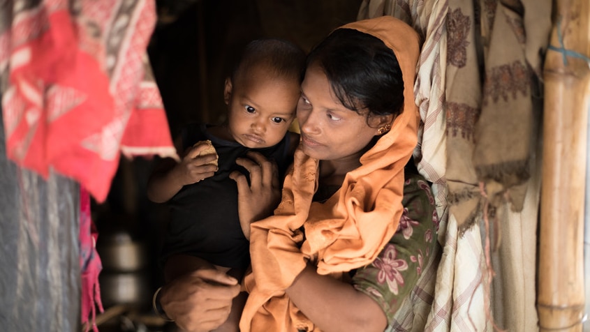 Rohingya mother Bitani* stands in her makeshift tent in Cox's Bazar, Bangladesh with her 18 month-old daughter.