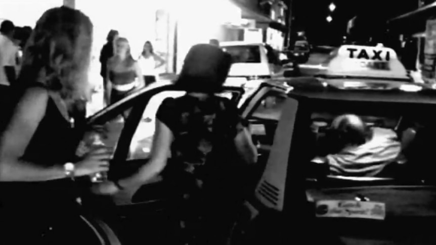 Black and white still of two young women getting into a taxi at night.