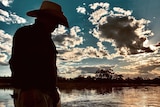 The silhouette of a man with an akubra on a speed boat in the river