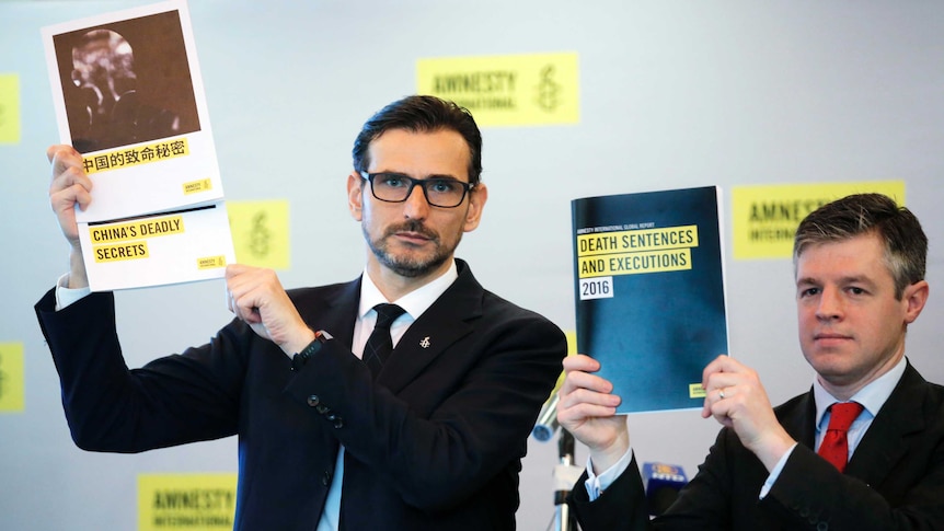 Amnesty International East Asia Director Nicholas Bequelin (left) holds up the report.